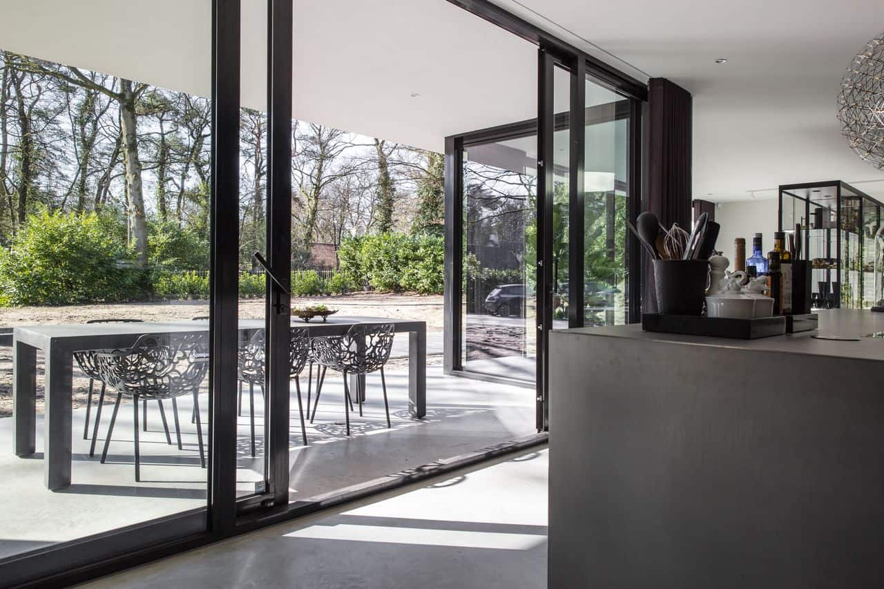 Gevlinderde betonvloer en een gevlinderd betonnen terras in Nijmegen met een grijs kookeiland op de binnenvloer en op de buitenvloer staat een grijze tafel.