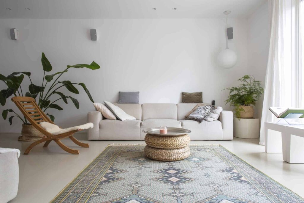 PU gietvloer van Willem Designvloeren in de woonkamer in Zeist. Hierop licht een licht gekleurd vloerkleed, staat een houten stoel en een beige bank. Ook staat er nog een grote plant op de PU gietvloer.