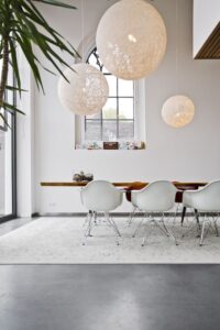Gevlinderde betonvloer van Willem Designvloeren in de woning in een oud kerkje in Leerdam. Hierop staat een houten tafel met witte stoelen.