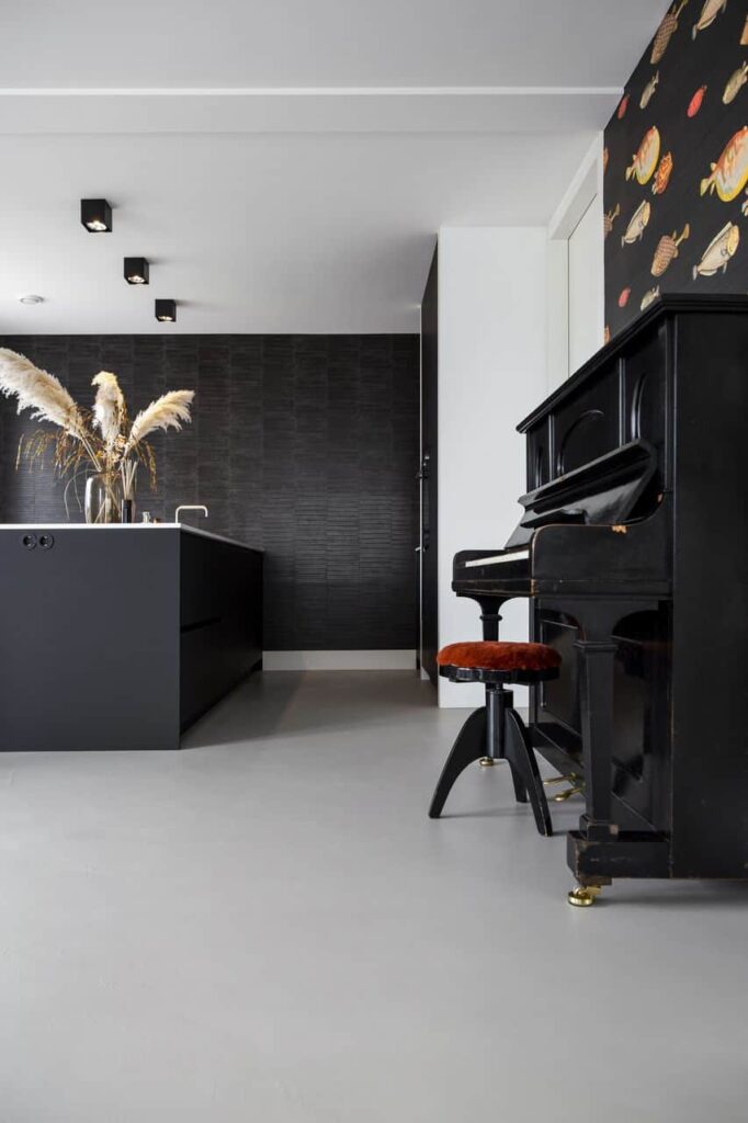 Beton ciré vloer in de keuken gecombineerd met een zwart kookeiland en een zwarte piano.