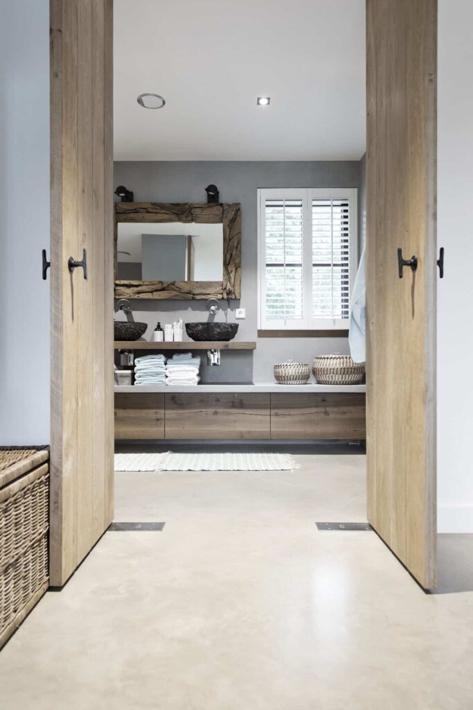 Badkamer met een gevlinderde betonvloer van Willem Designvloeren gecombineerd met veel houten details.