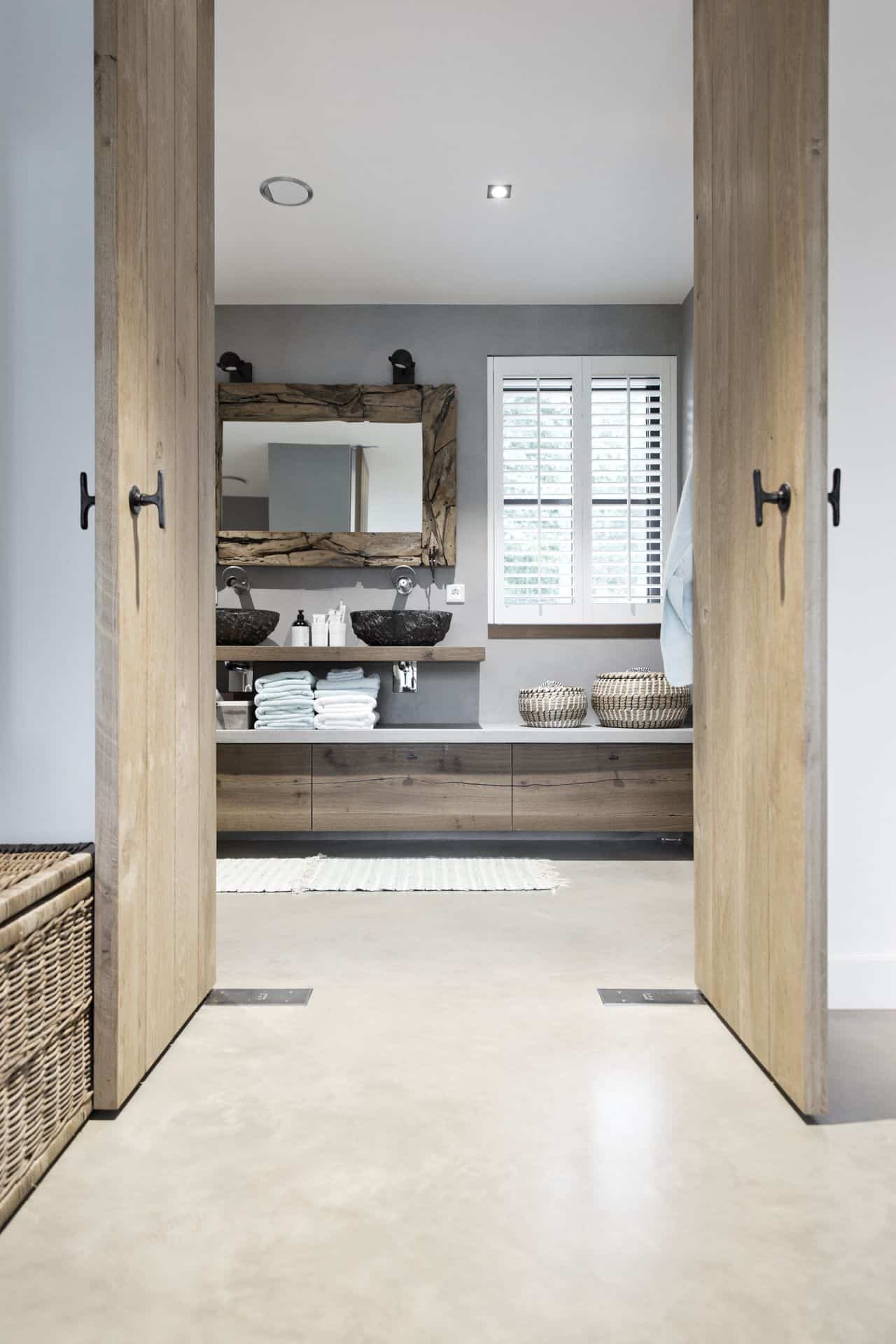 Badkamer met een gevlinderde betonvloer van Willem Designvloeren gecombineerd met veel houten details.