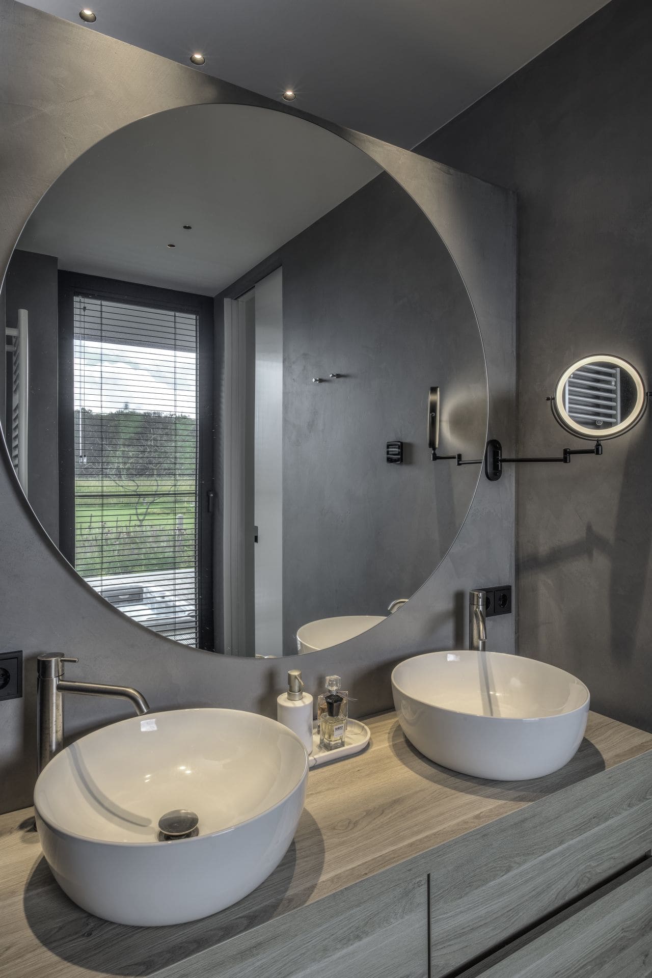 Beton ciré op de wanden in de badkamer in Wijhe met een houten meubel met hierop twee witte waskommen.