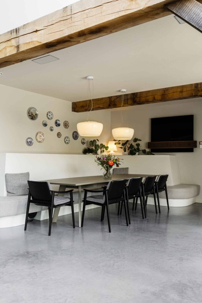 Eetgedeelte in deze vrijstaande woning in Oss gecombineerd met een gevlinderde betonvloer een grijze tafel en zwarte stoelen 1