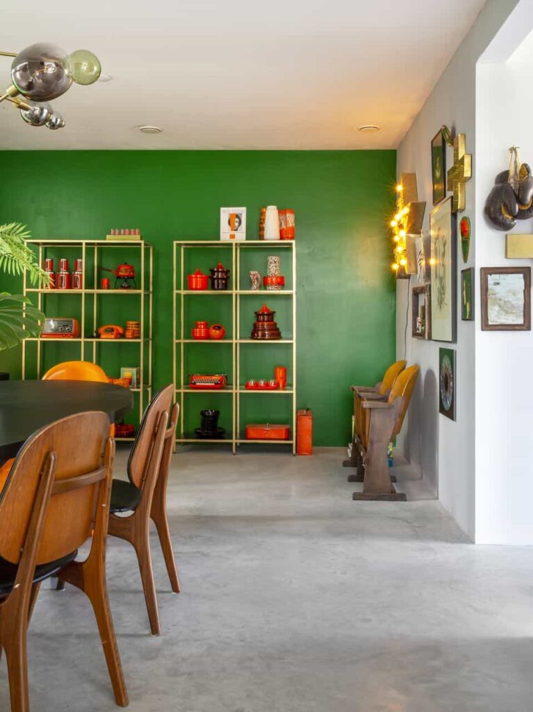 Eetkamer met een groene wand, houten details en een gevlinderde betonvloer van Willem Designvloeren.