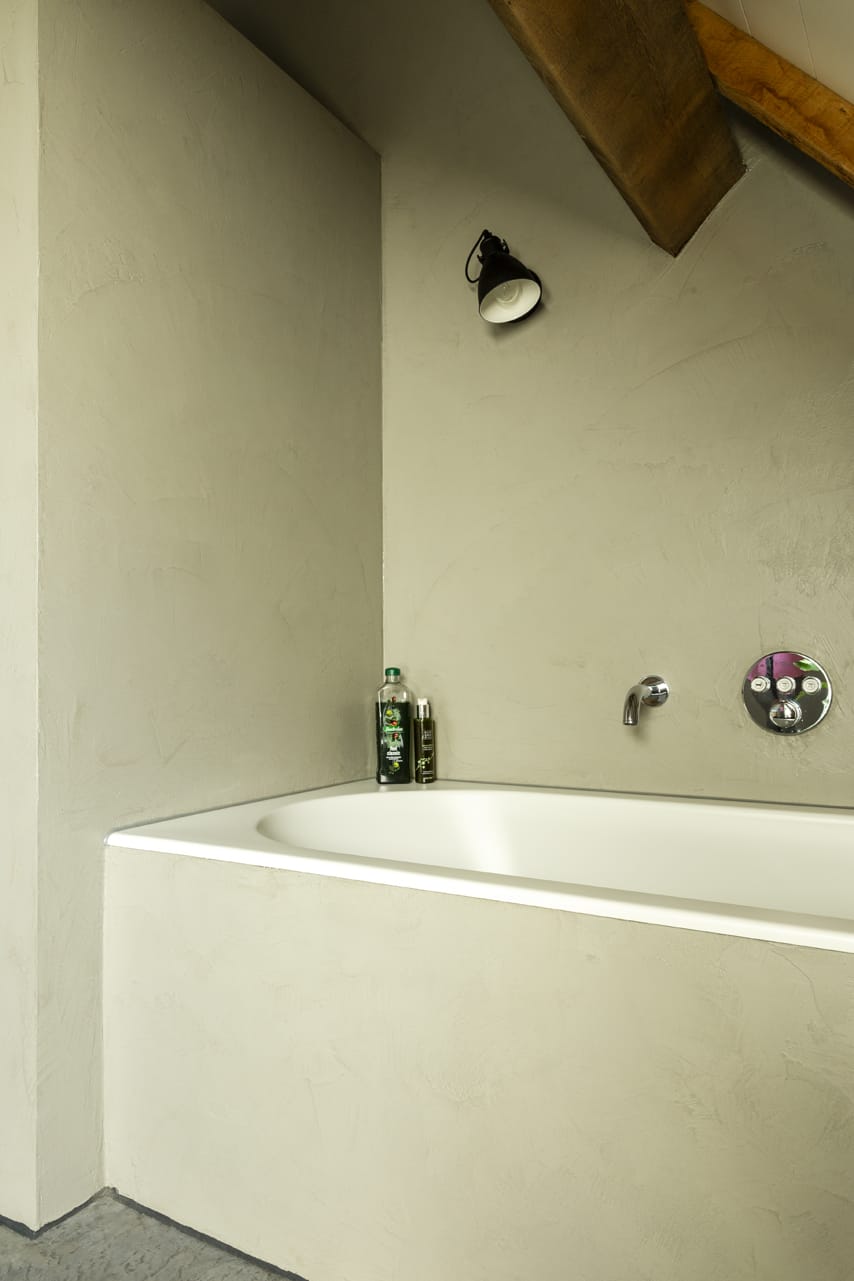 Gevlinderde betonvloer en beton ciré wand in de badkamer.