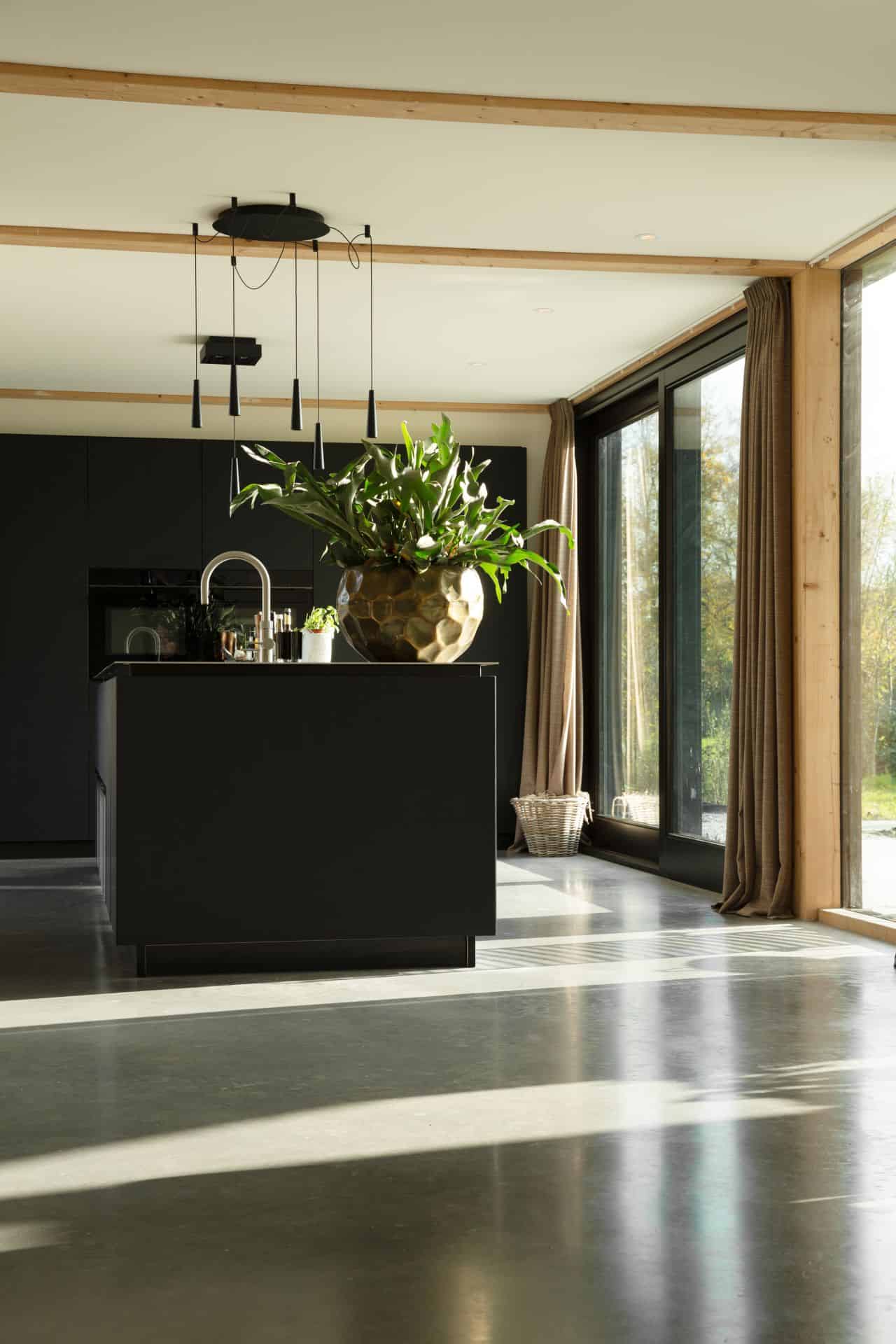 Gevlinderde betonvloer en betonnen terras in Zeist met daarop een zwarte keuken.