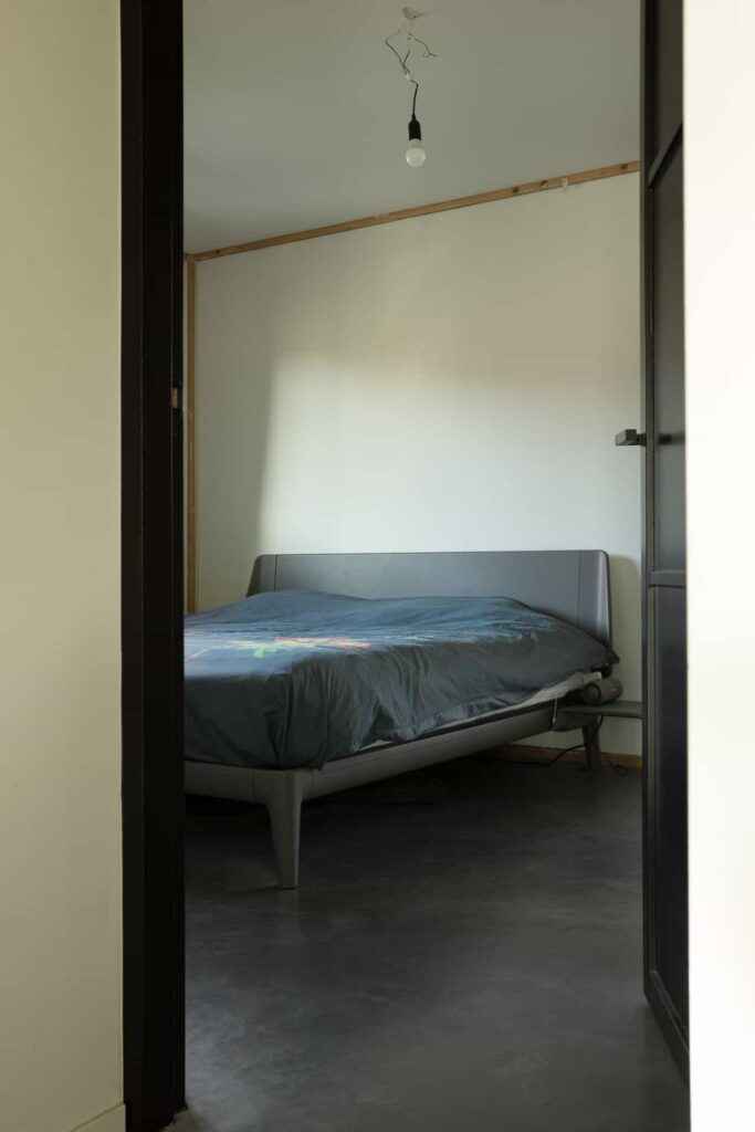 Gevlinderde betonvloer en betonnen terras in Zeist. Op de afbeelding zie je de slaapkamer met een grijs bed.