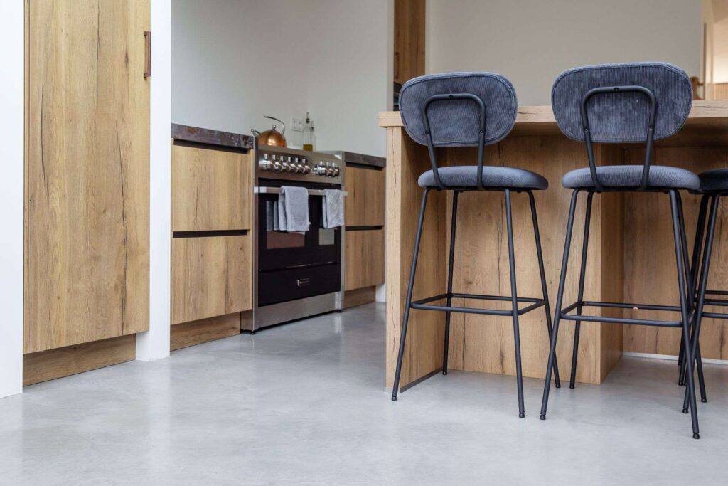 Gevlinderde betonvloer gecombineerd met een houten én roze keuken.