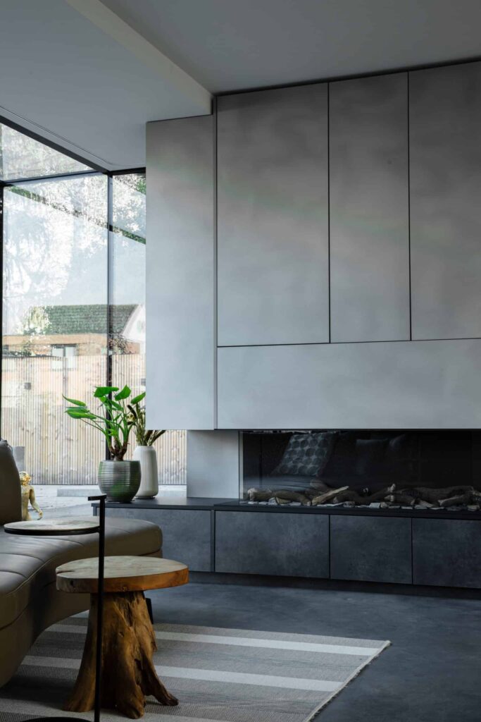 Gevlinderde betonvloer in Bemmel in de woonkamer. Hier ligt een grijs kleed met een houten tafeltje en zit een haard in de wand 1