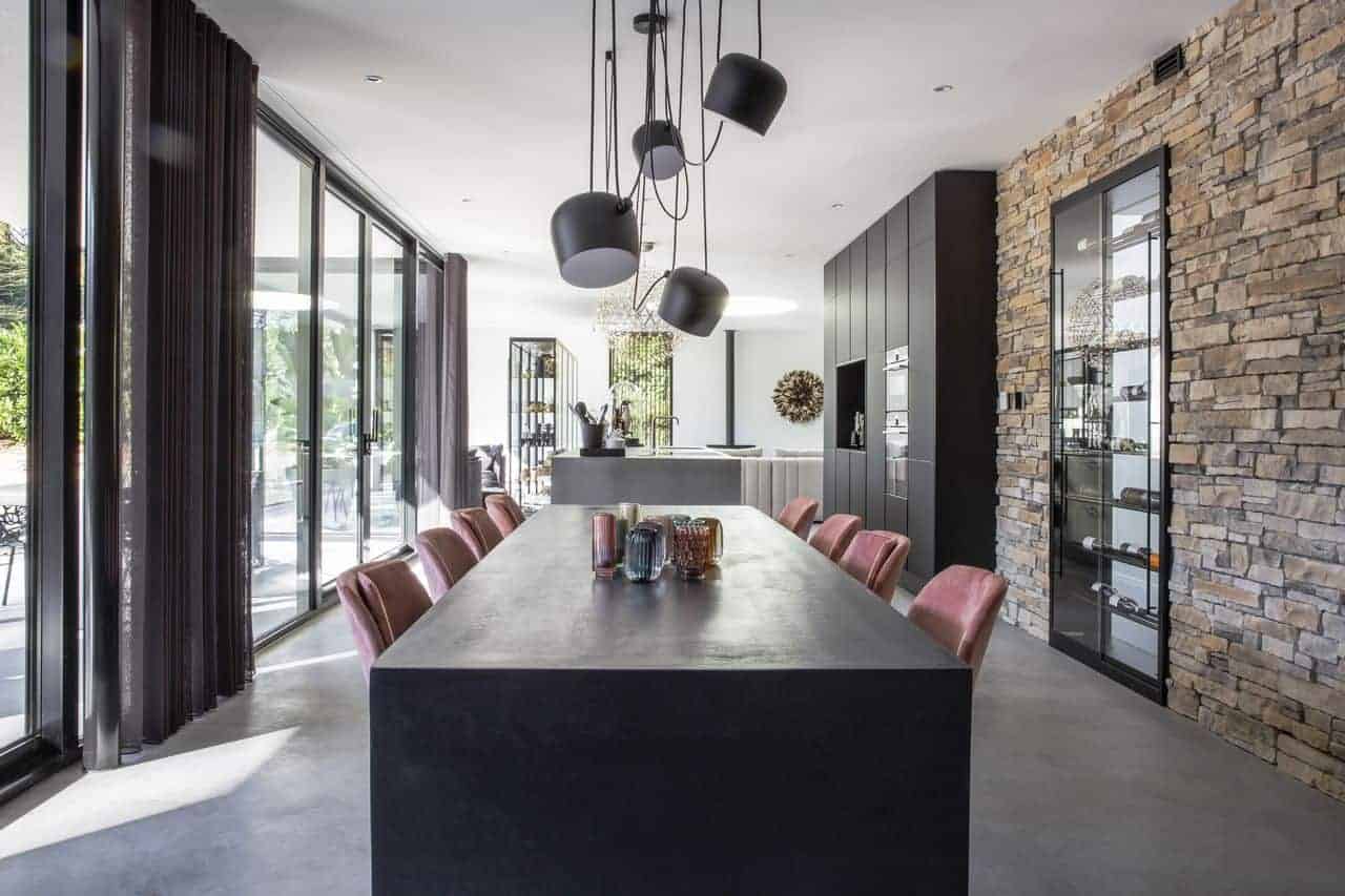 Gevlinderde betonvloer in Nijmegen gecombineerd met een stenen muur, zwarte tafel en daaraan roze stoelen.