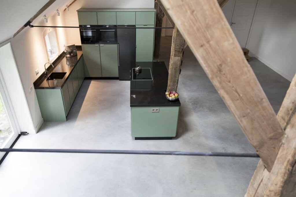 Gevlinderde betonvloer in Rijswijk gecombineerd met een groene keuken.