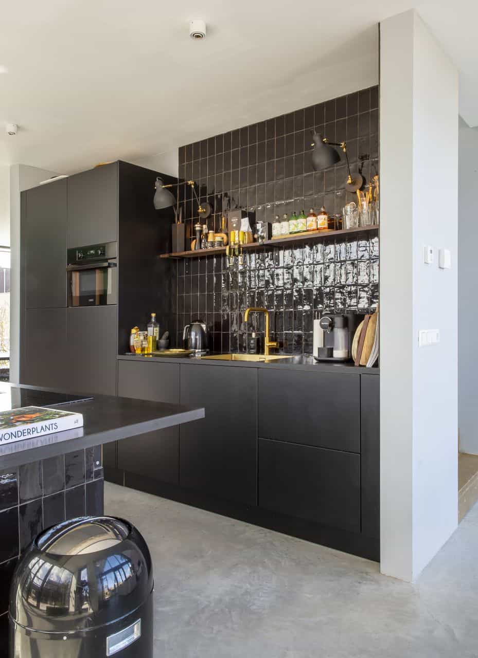 Gevlinderde betonvloer in Schoonhoven gecombineerd met een zwarte keuken en gouden details.