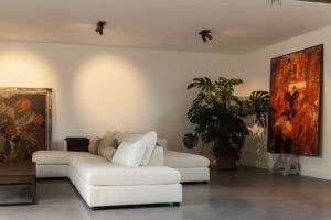 Gevlinderde betonvloer in de woonkamer, gecombineerd met een lichte bank en kunst.