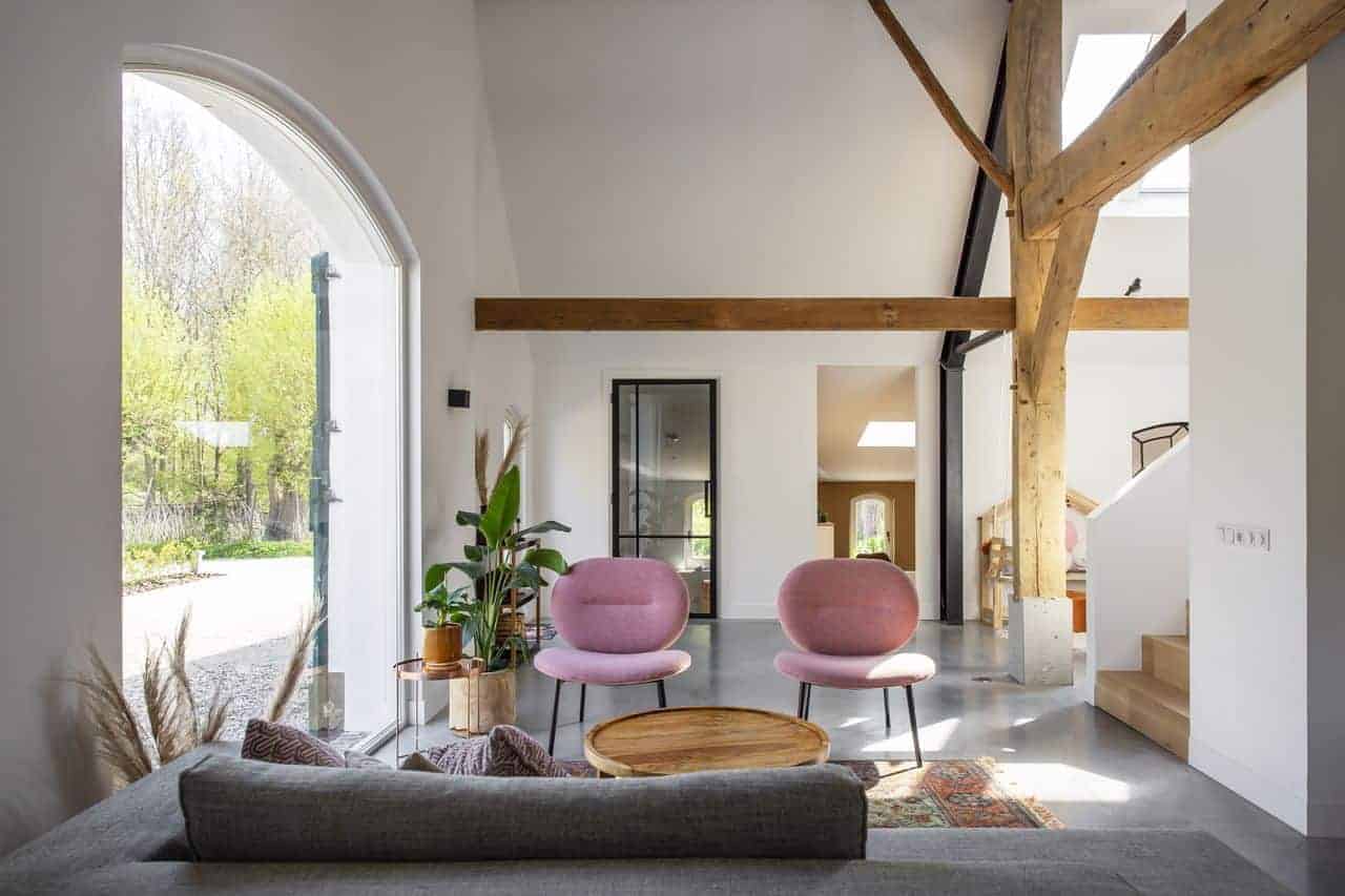 Gevlinderde betonvloer in de woonkamer in Ressen gecombineerd met een grijze bank en roze stoeltjes.