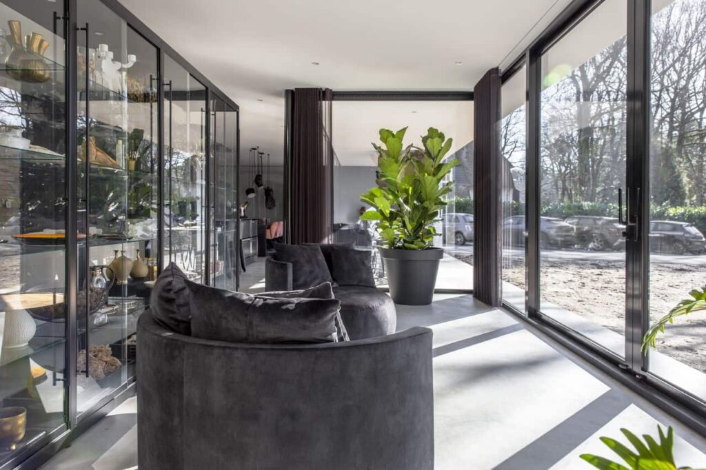 Gevlinderde betonvloer van Willem Designvloeren in Nijmegen in de tuinkamer. Hierop staan twee grote grijze stoelen.