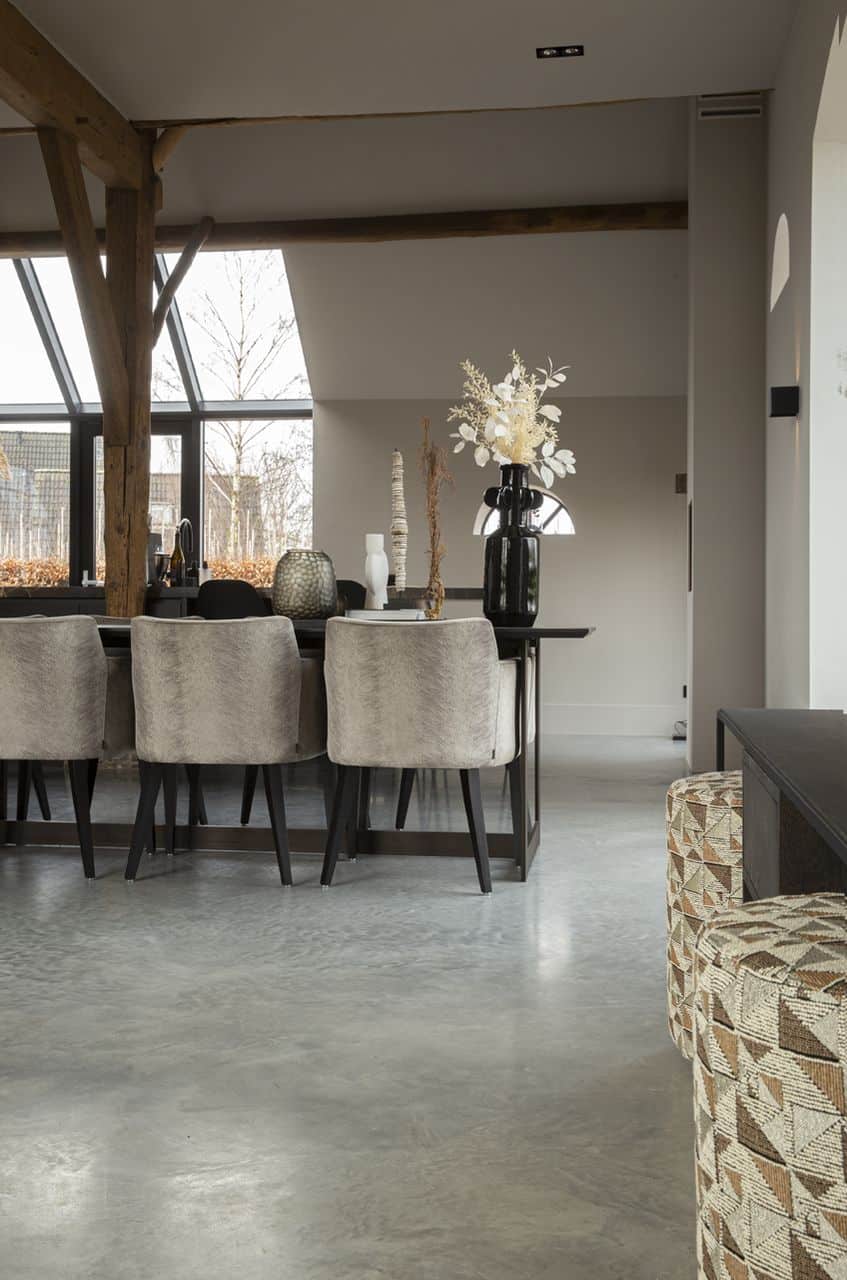 Gevlinderde betonvloer van Willem Designvloeren in Ochten. Hierop staat een zwarte tafel en daaraan grijze stoelen.