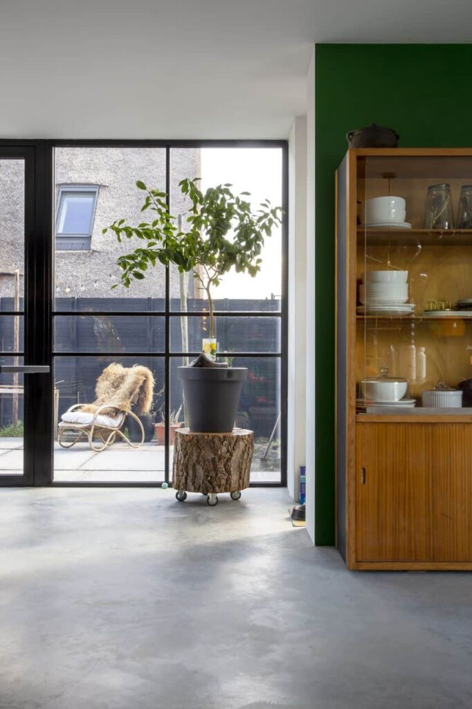 Gevlinderde betonvloer van Willem Designvloeren in Schoonhoven met daarop een houten kast, en een boomstam als tafeltje met daarop een plant.