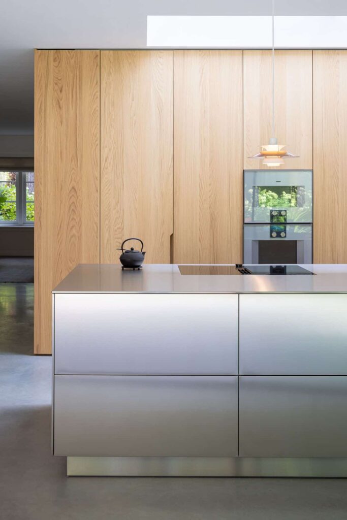 Gevlinderde woonbetonvloer in Zeist met een aluminium kookeiland en een houten keuken.