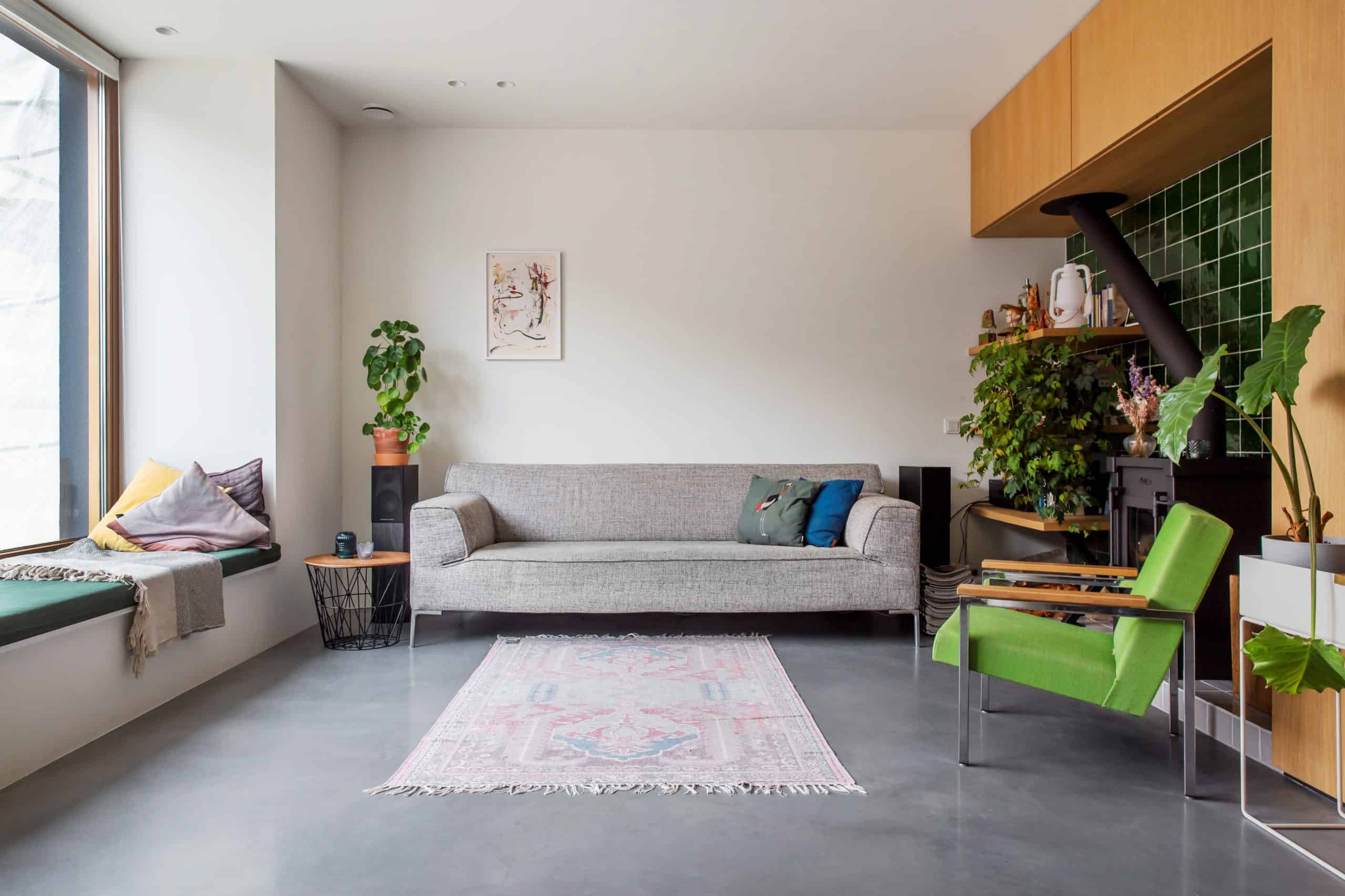 Grijze bank en groene stoel in amsterdam. Gecombineerd met een gevlinderde betonvloer