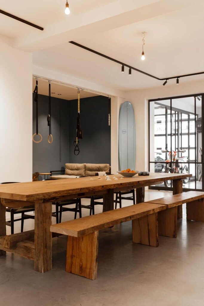 Houten eettafel met een houten bank in Den Haag op een gevlinderde betonvloer.