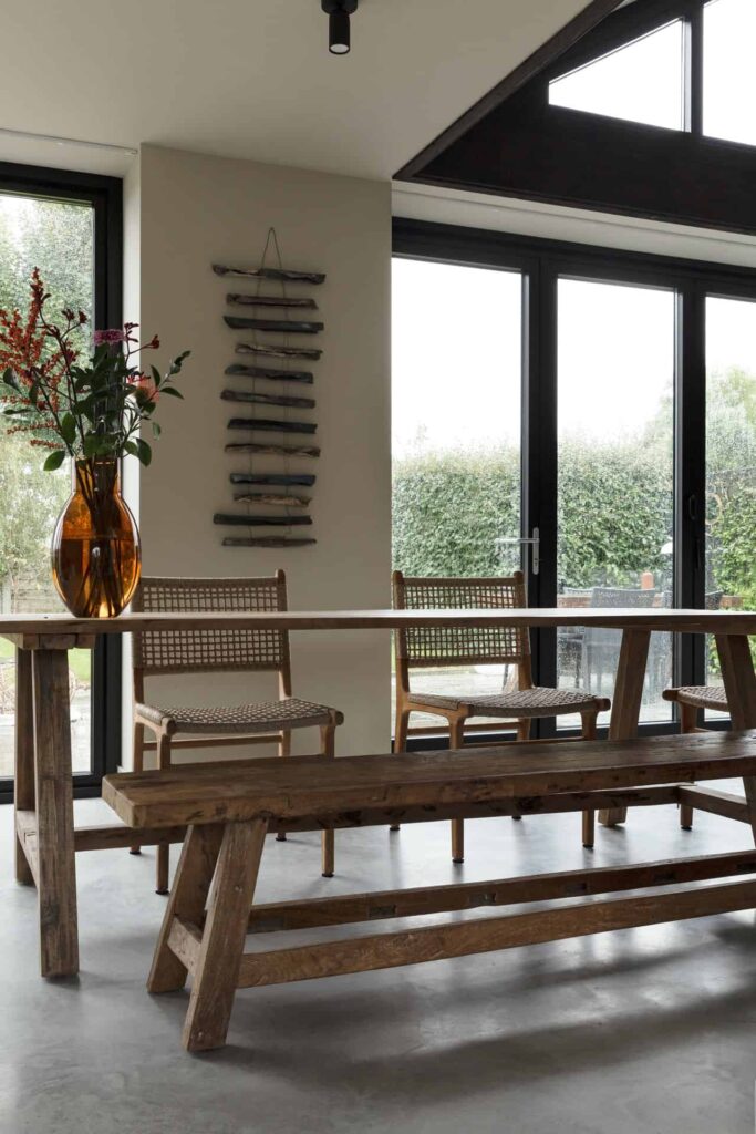 Houten eettafel met stoelen en een bankje in Rijnsburg. Dit staat op een gevlinderde betonvloer.