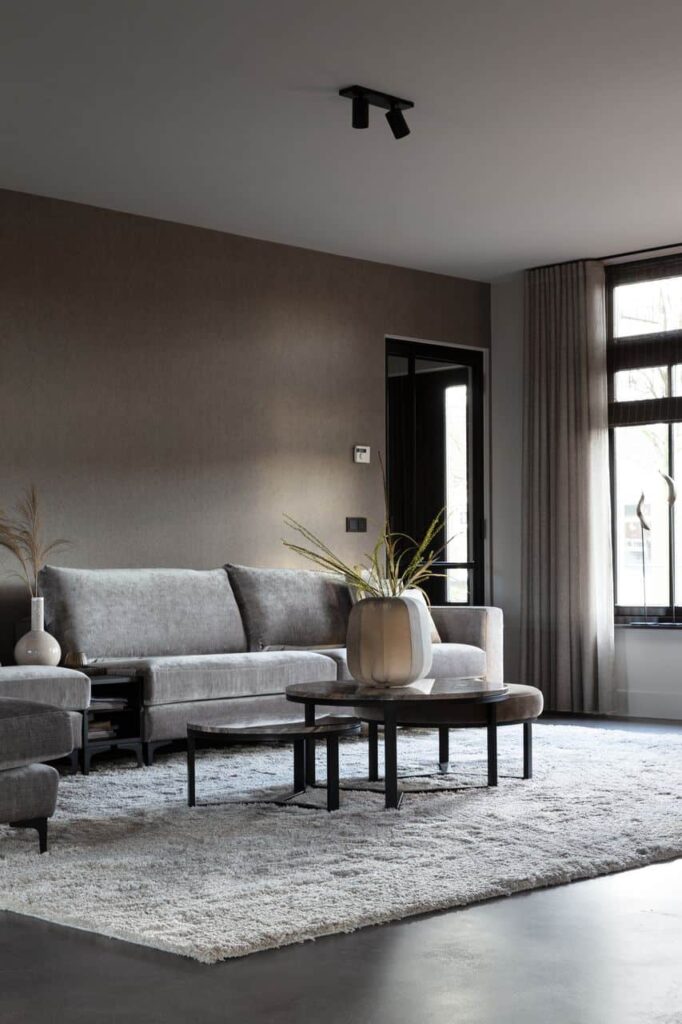 Italiaanse betonlook vloer in Opheusden in de woonkamer met daarop een grijze bank op een grijs vloerkleed.