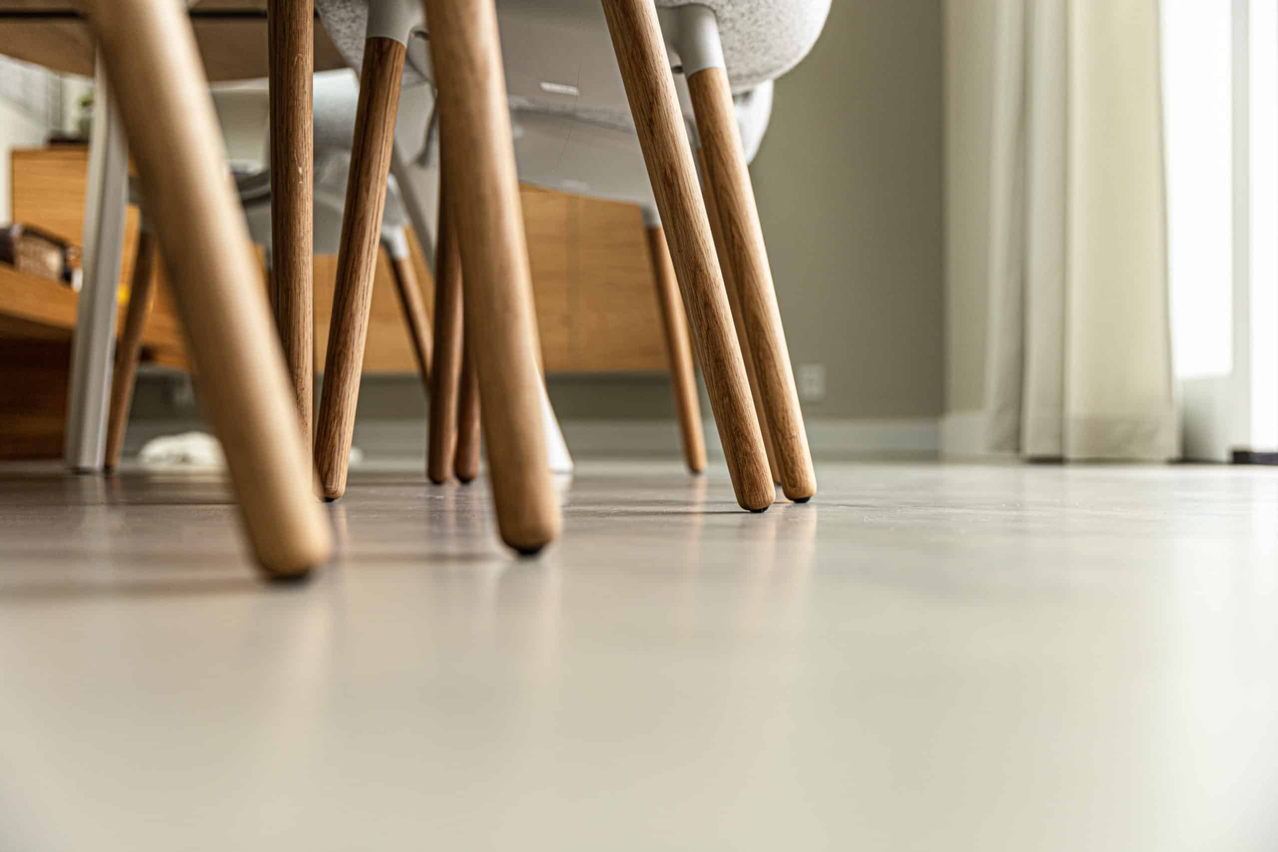 Italiaanse betonlook vloer in Soesterberg met daarop stoelen met houten poten.