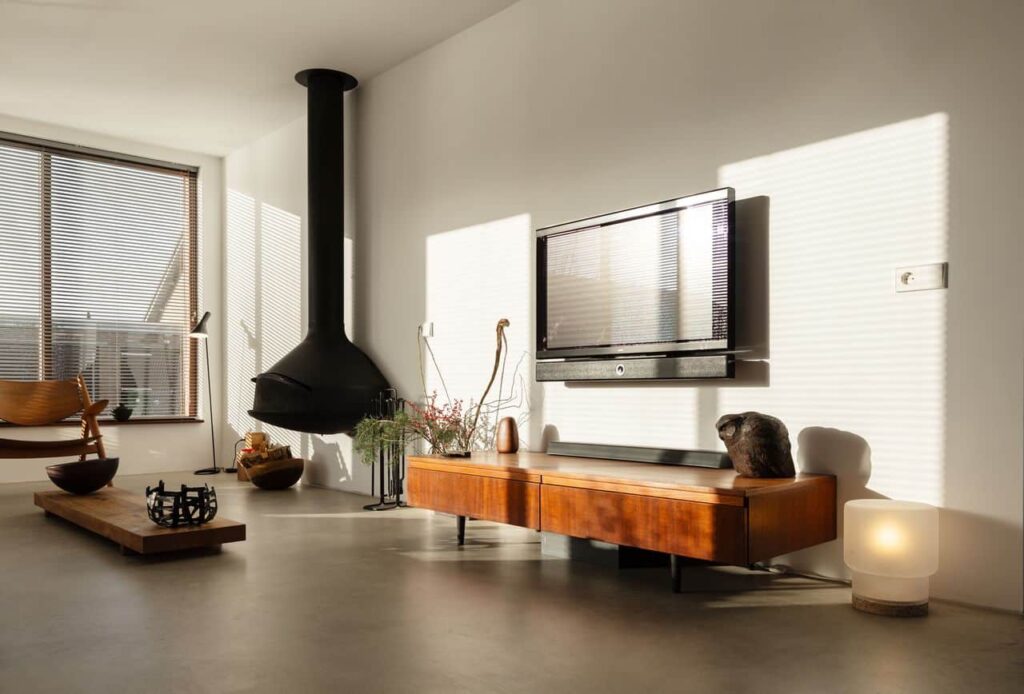 Italiaanse betonlook vloer in de woonkamer in Oostzaan gecombineerd met houten meubels en een zwarte haard.