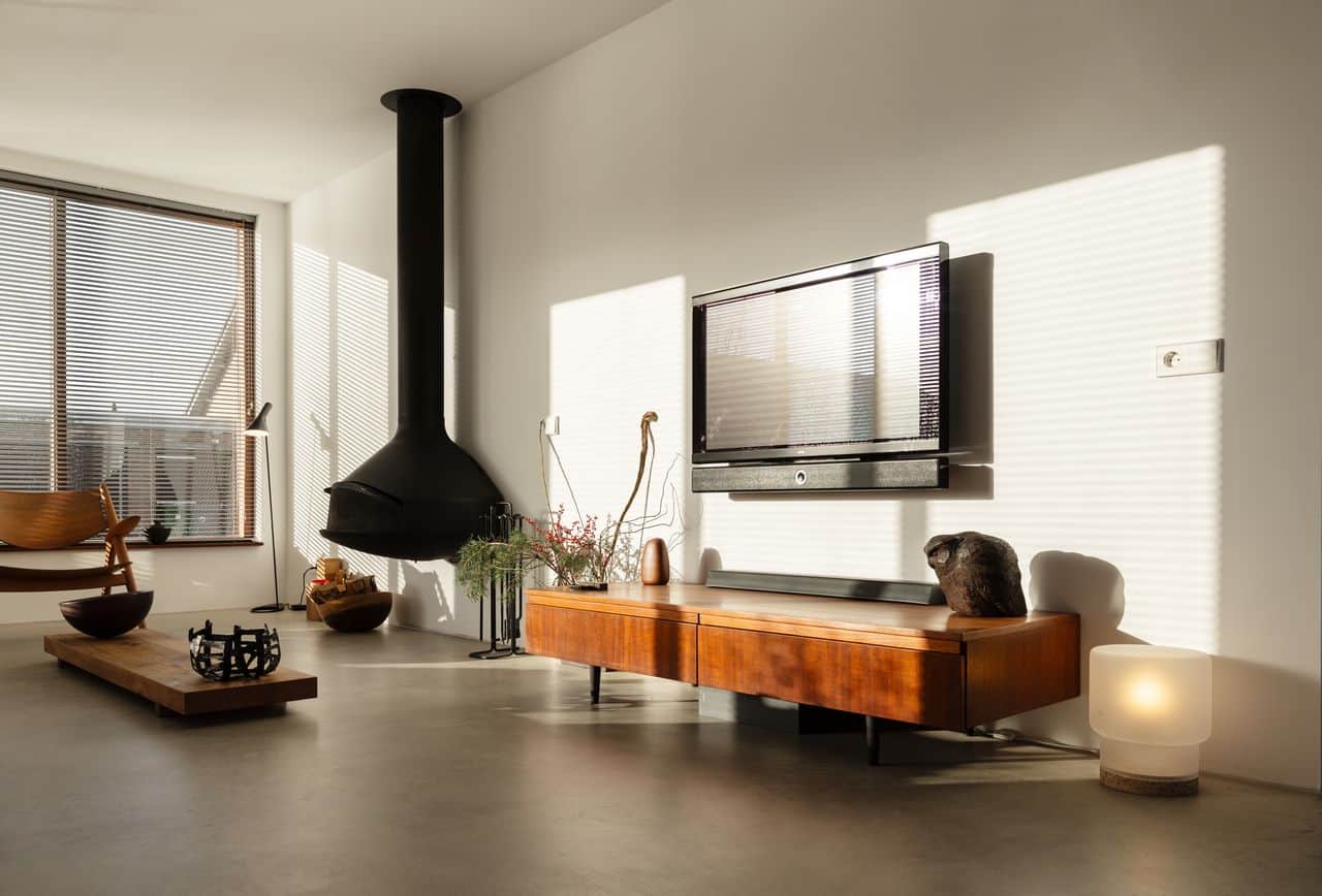 Italiaanse betonlook vloer in de woonkamer in Oostzaan gecombineerd met houten meubels en een zwarte haard.