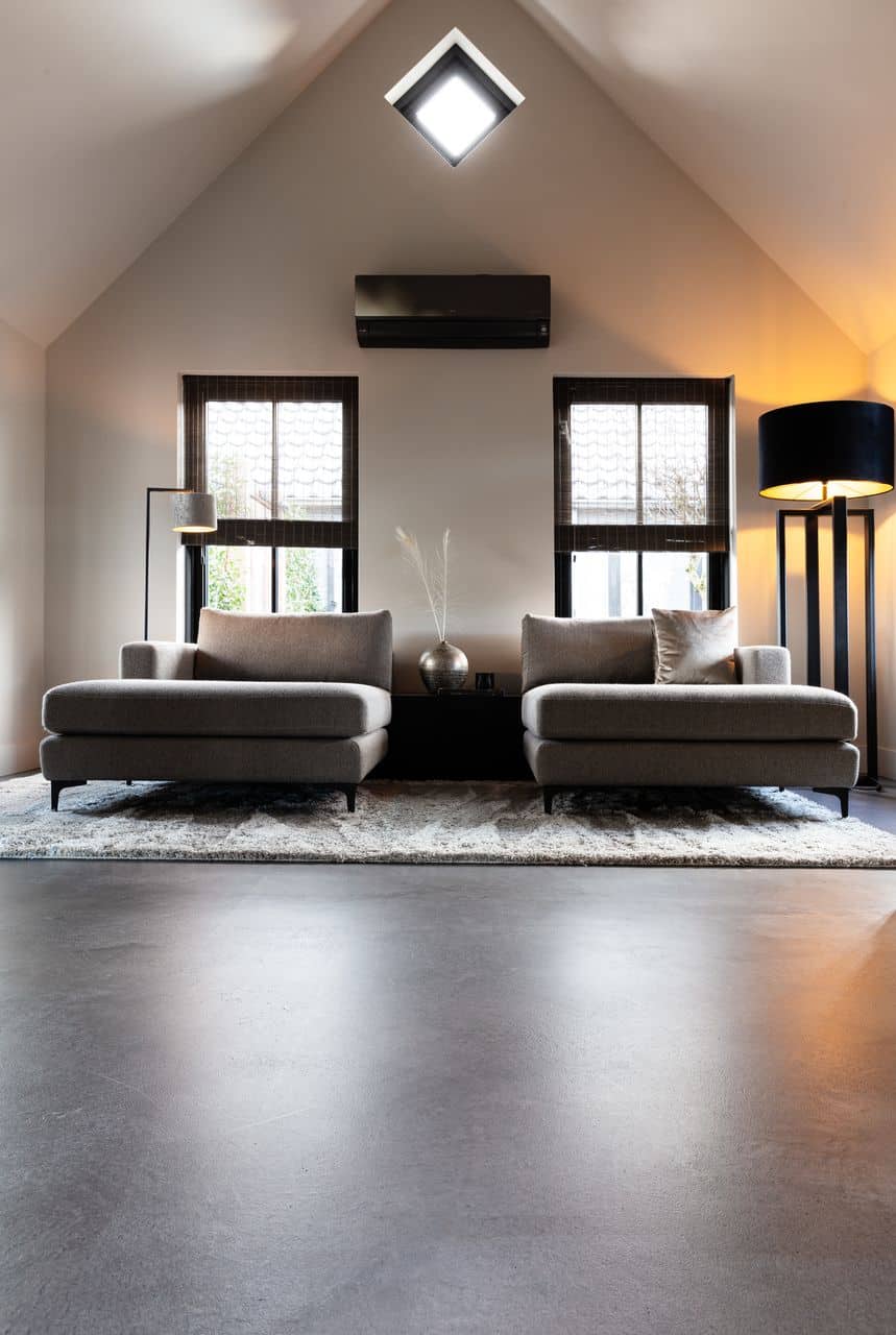 Italiaanse betonlook vloer van Willem Designvloeren in een landelijke woning in Opheusden met daarop twee loveseats.