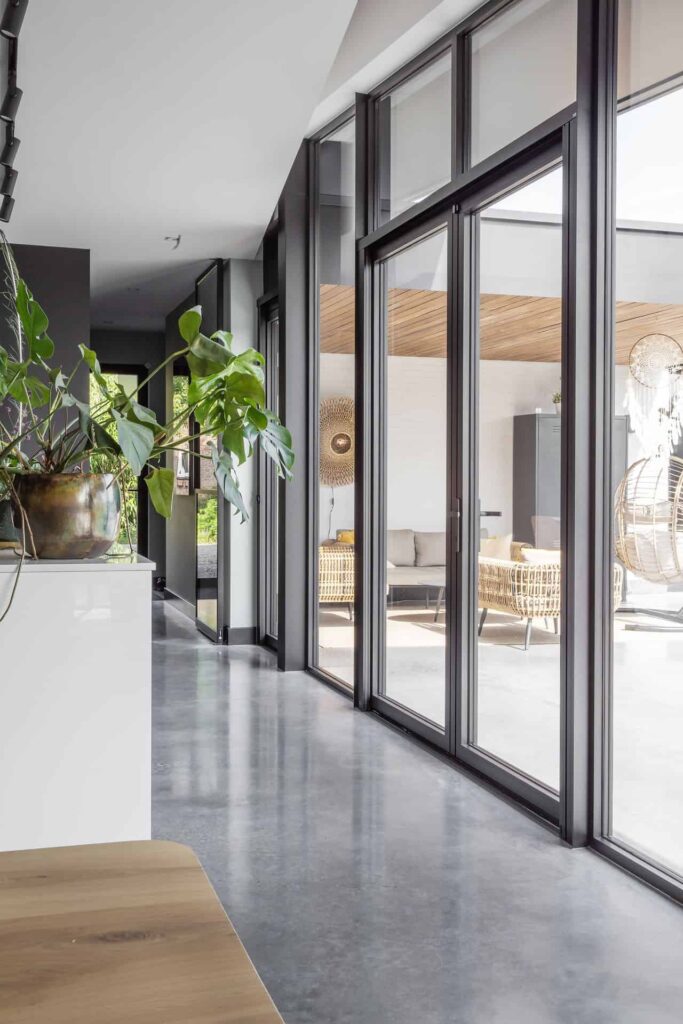 Kijkje van binnen naar buiten met een gevlinderde betonvloer en een gevlinderd betonnen terras.