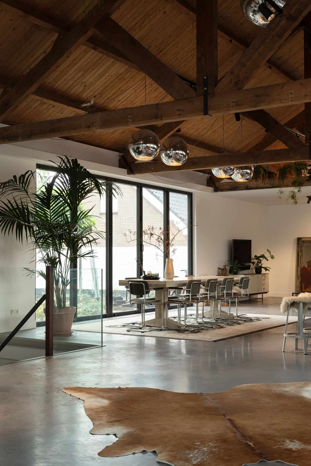 Modern, industrieel interieur met een houten balkenplafond en een gevlinderde woonbeton vloer.