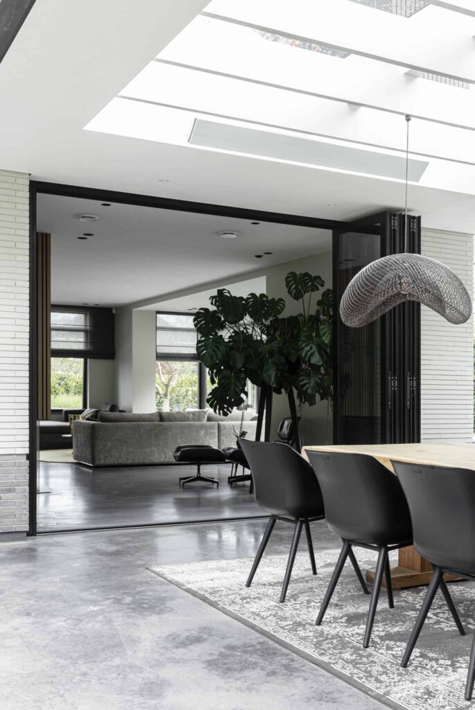 Overloop van het gevlinderd betonnen terras naar de gevlinderde betonvloer in huis.