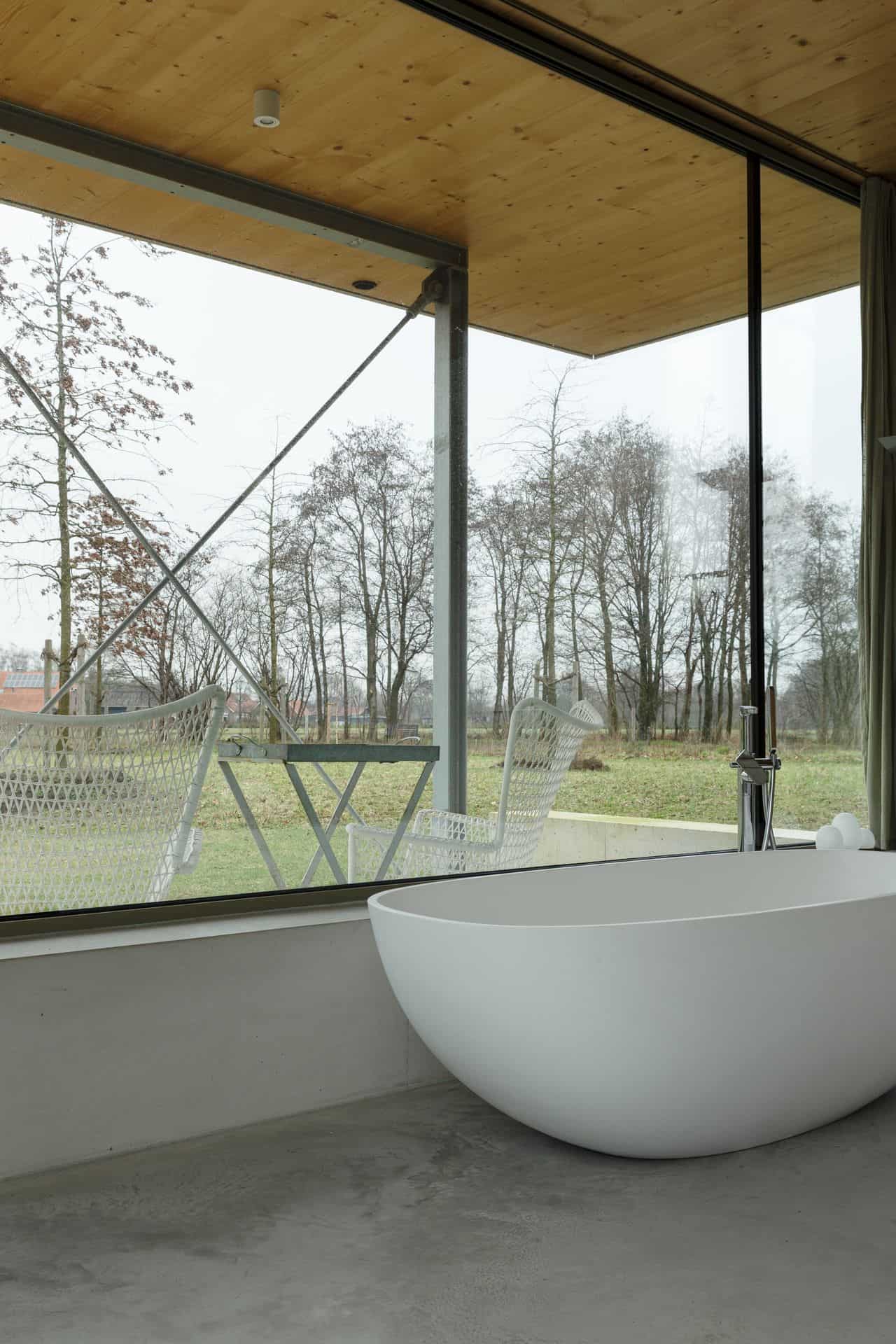 Slaapkamer ergens in de Achterhoek met daarin een wit bad op een gevlinderde betonvloer.