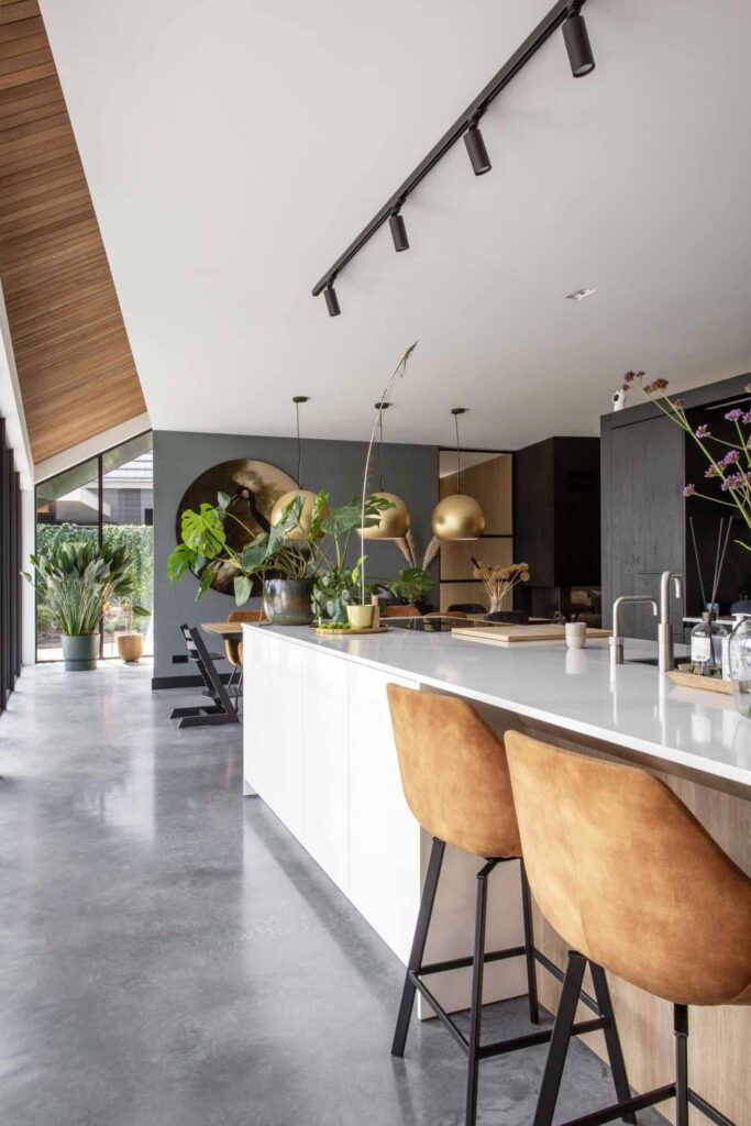 Wit kookeiland in Nuenen met een gevlinderde betonvloer. Hieraan staan 2 barkrukken.