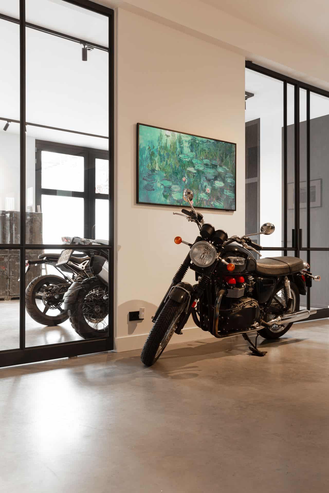 Woning in Den Haag met een gevlinderde betonvloer. Op de betonvloer staat een motor. Achter de stalen deuren staan nog twee motors.