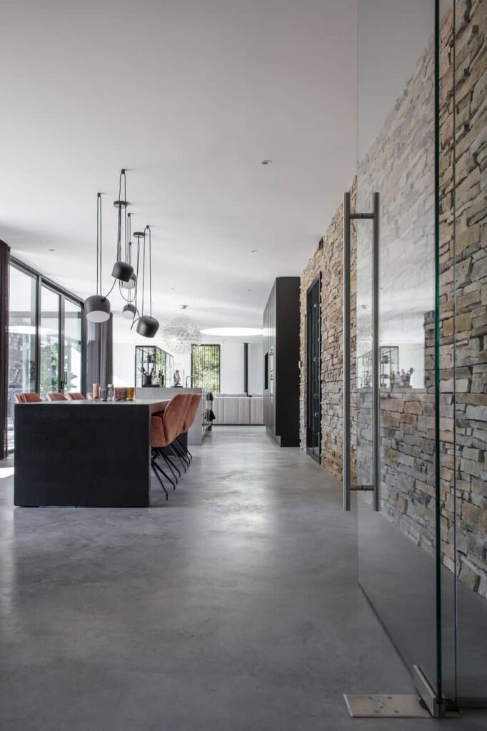 Woning in Nijmegen met een gevlinderde betonvloer in de keuken, woonkamer en eetkamer. De wand is van robuuste stenen.
