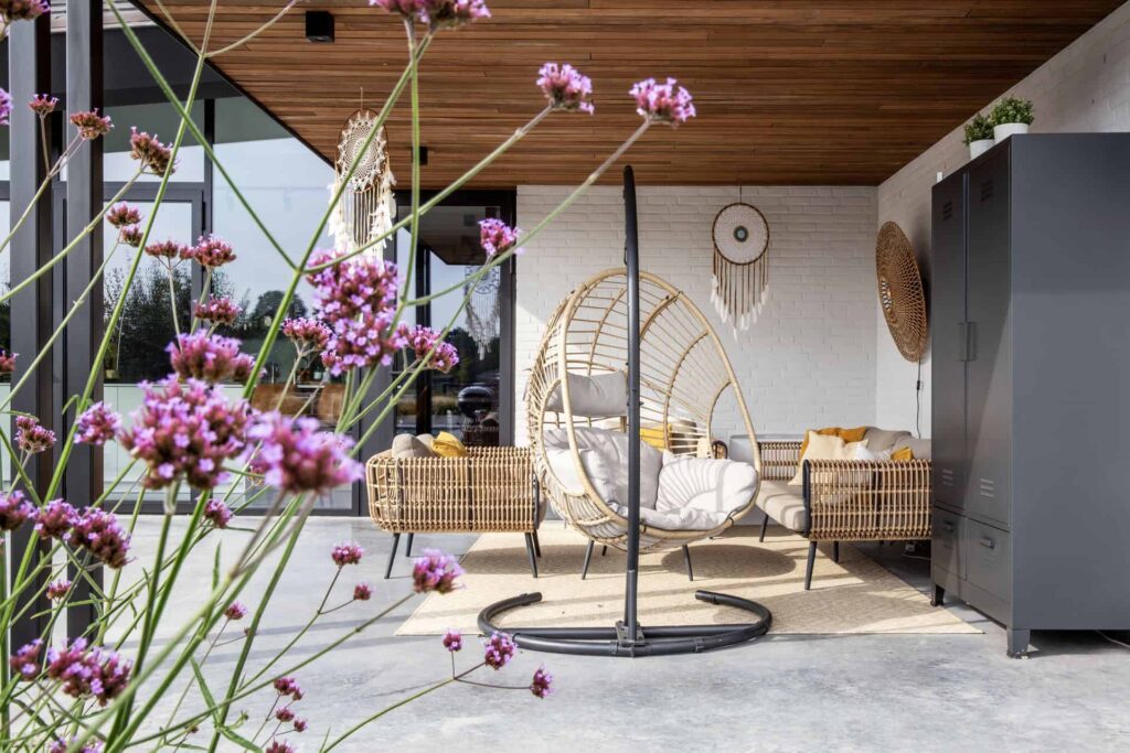 Woning in Nuenen met een gevlinderd betonnen terras en hierop een rieten tuinset