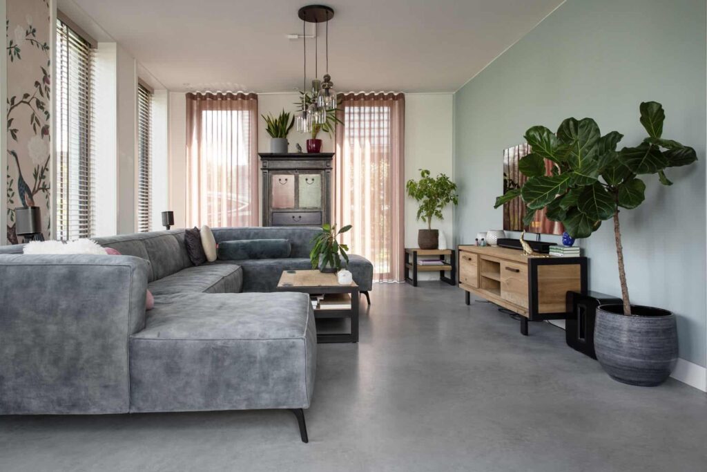 Woonkamer in Ede met een grijze bank, roze gordijnen, een houten tv-meubel en een gevlinderde betonvloer
