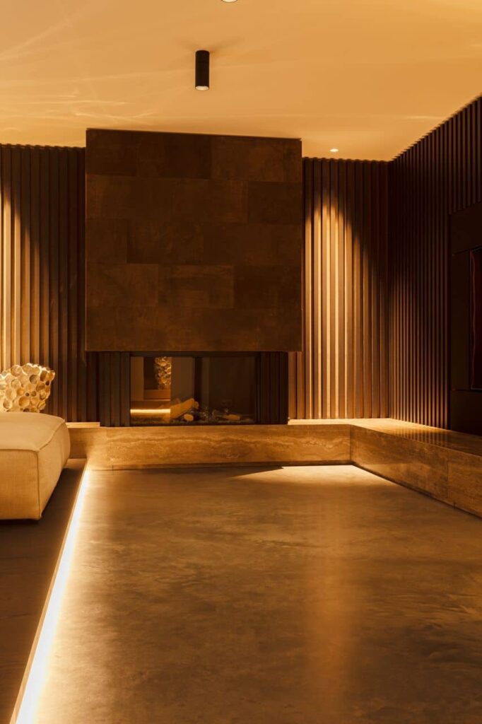 Woonkamer met een gevlinderde betonnen vloer gecombineerd met een prachtige haard en zithoek.