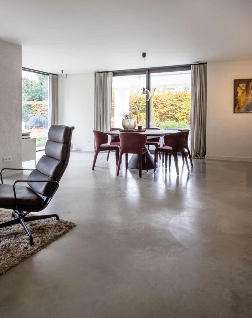 Zwarte eettafel met daaraan paarse stoelen in Waalwijk, op een gevlinderde betonvloer