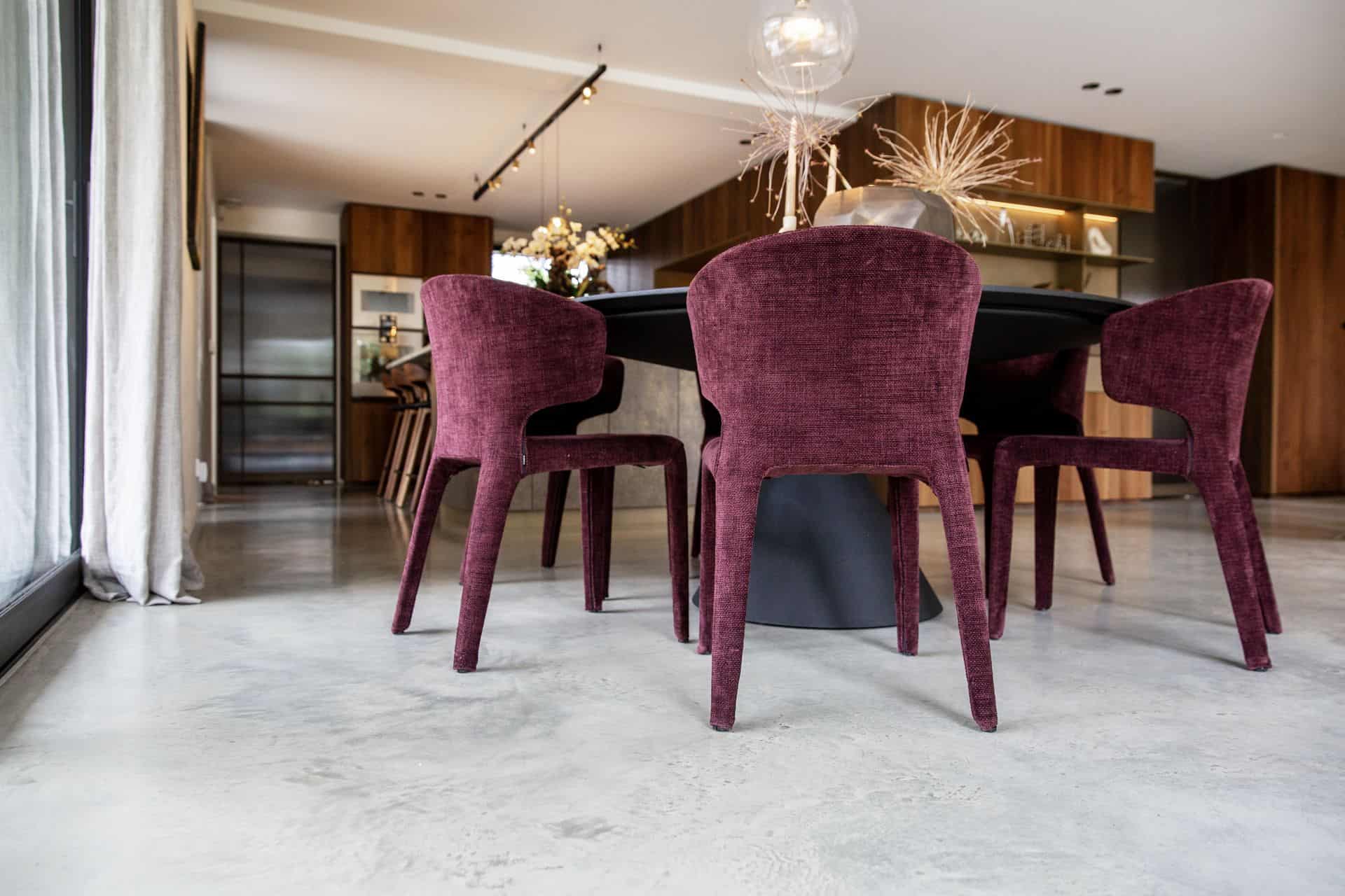 Zwarte eettafel met daaraan paarse stoelen in Waalwijk. Deze staan op een gevlinderde betonvloer.