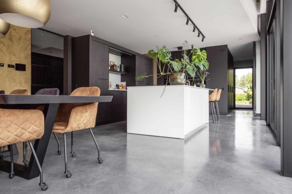 Zwarte keuken met een wit kookeiland in Nuenen, gecombineerd met een gevlinderde betonvloer.