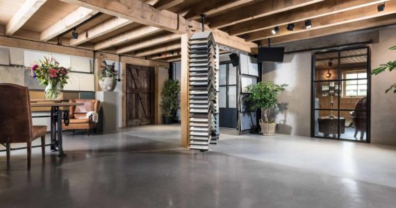 Showroom van Willem Designvloeren in Opheusden met een gevlinderde betonvloer, beton ciré vloer en een PU Gietvloer. Ook zie je verschillende samples van verschillende vloeren staan en liggen.