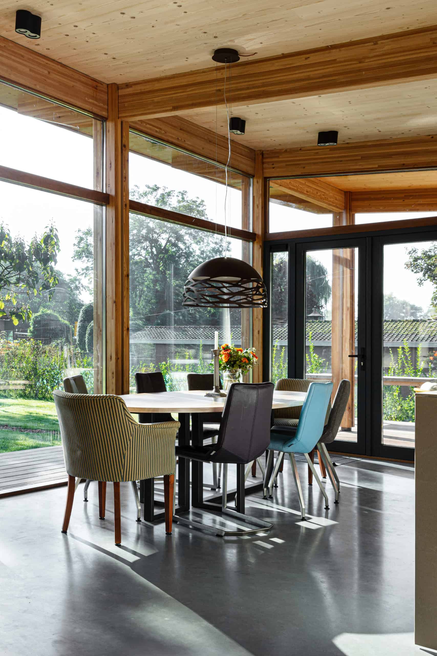 Eettafel met verschillende kleuren stoelen in Rhenen met een gevlinderde betonvloer van Willem Designvloeren