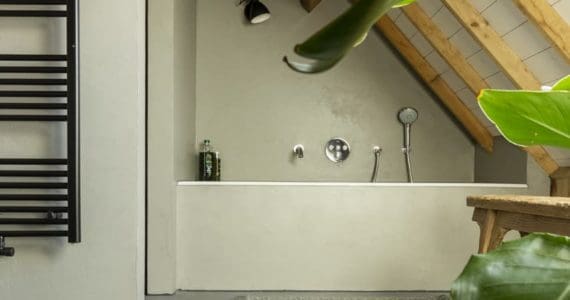 Beton ciré muur in de badkamer. Gevlinderde woonbeton vloer in de badkamer. Beton cire kleur