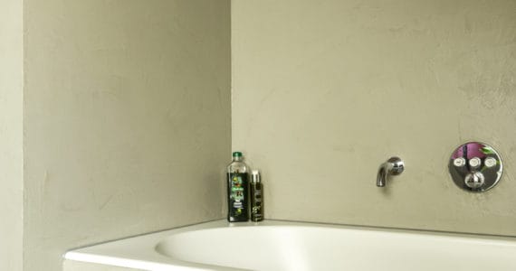 Gevlinderde betonvloer en beton ciré wand in de badkamer.