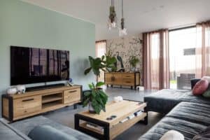 Woning in Ede met een gevlinderde betonvloer in de woonkamer, hierin staat een grijze bank, een houten bijzettafel en een houten tv-meubel Gepolierde beton onderhoud