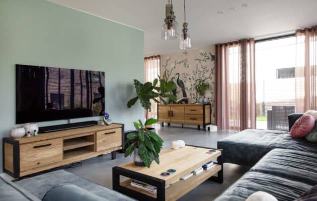 Woning in Ede met een gevlinderde betonvloer in de woonkamer, hierin staat een grijze bank, een houten bijzettafel en een houten tv-meubel